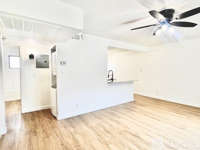 A room with a ceiling fan and light, a door, and a wall-mounted light fixture.