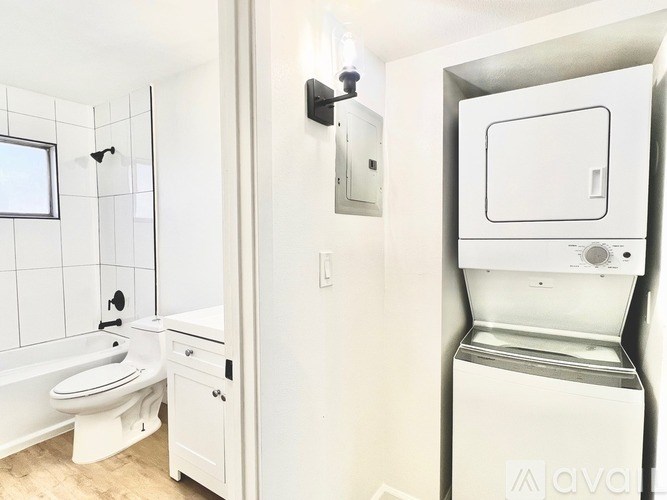 A white bathroom with a toilet, sink, and a washer and dryer.