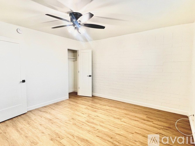 A room with a ceiling fan and wooden flooring.