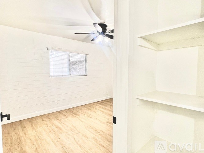 A room with a ceiling fan and a window with blinds.