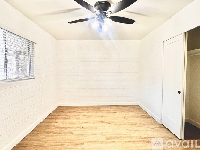A room with a ceiling fan and wooden flooring.