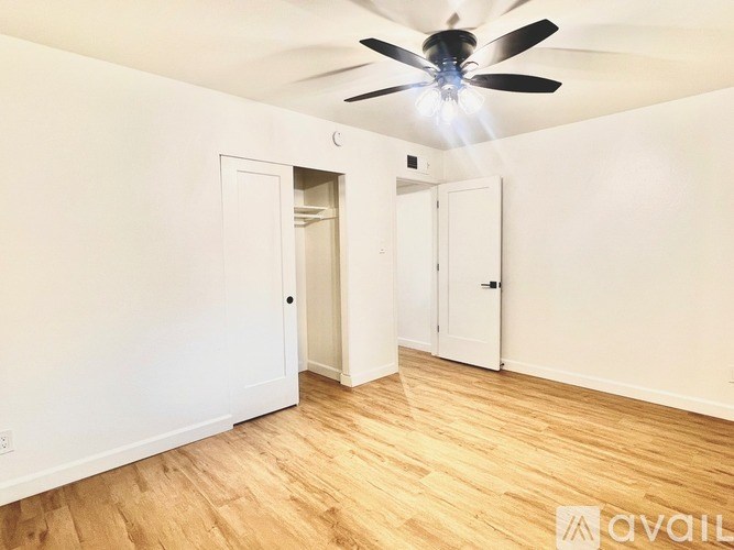 A room with a ceiling fan and wooden flooring.