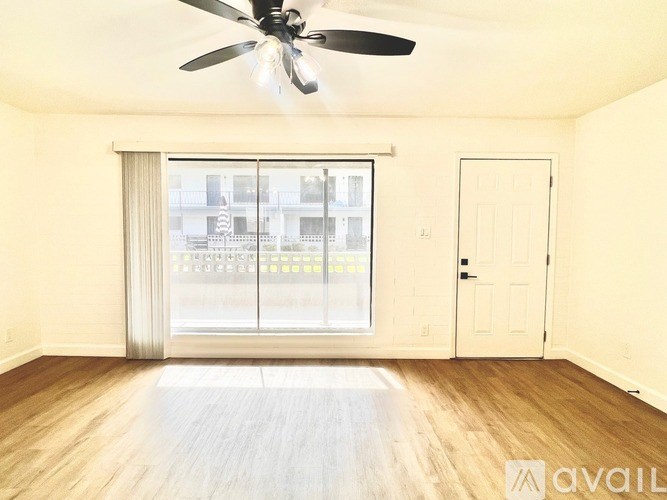 A room with a ceiling fan and sliding glass doors.