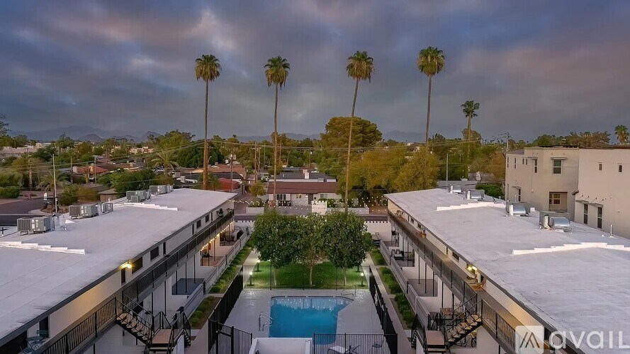 A view of a pool surrounded by buildings and palm trees.