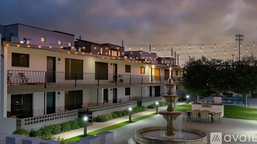 A building with a fountain in front of it at night.
