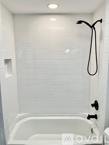 A white bathroom with a white tub and a black shower head.