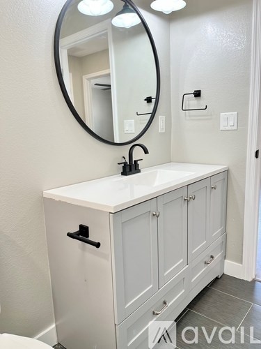 A white bathroom vanity with a round mirror above it.