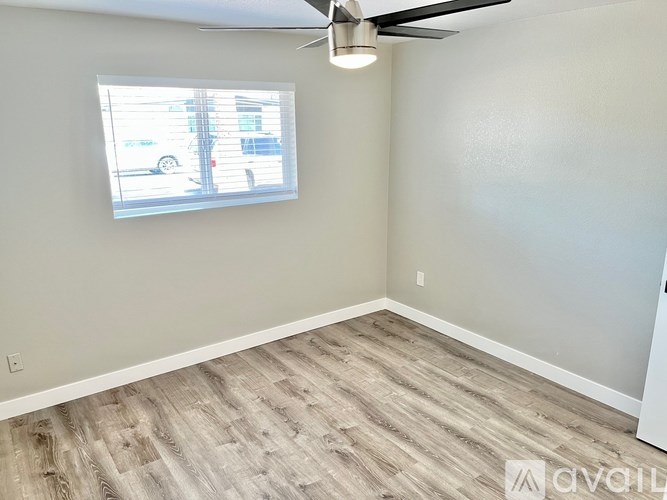 A room with a ceiling fan and a window showing a street view.