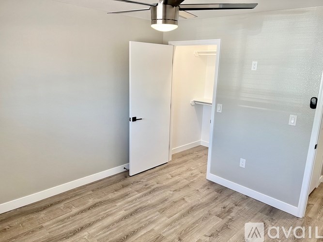 A room with a white door and a ceiling fan.