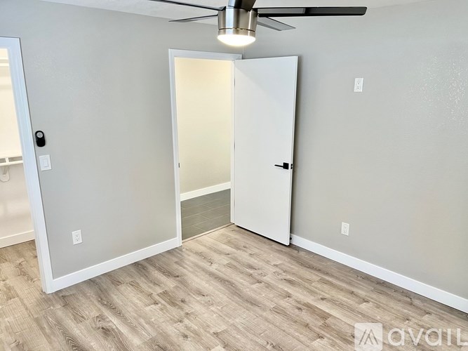 A room with a ceiling fan and a white door.
