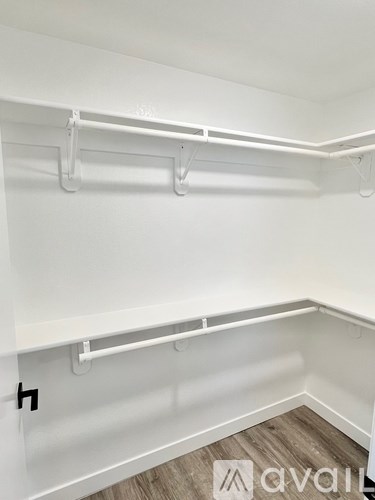 A white walk-in closet with shelves and a wooden floor.