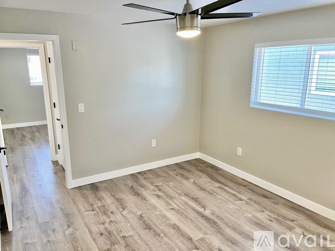 A room with a ceiling fan and a window with blinds.