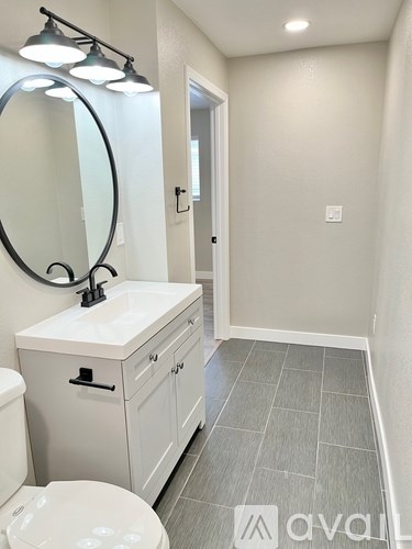 A bathroom with a toilet, sink, and mirror.