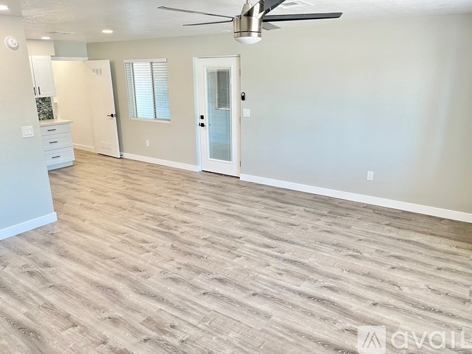 A room with a ceiling fan and wood flooring.