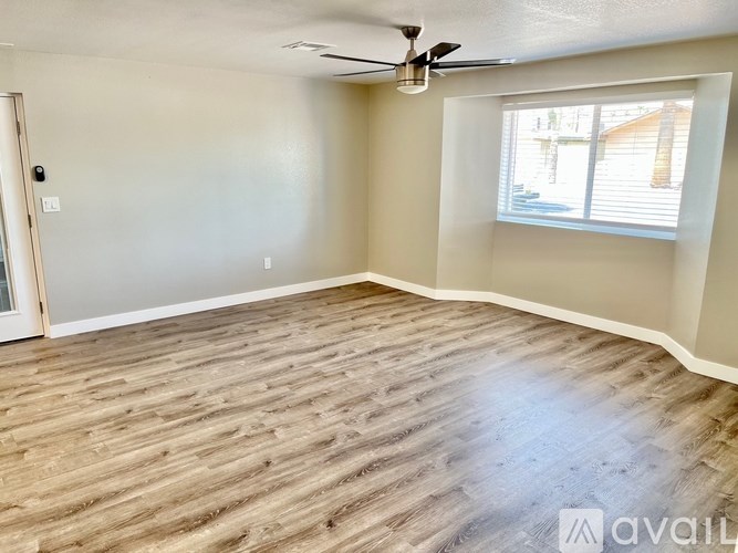 A room with a ceiling fan and wooden flooring.