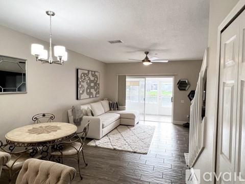 A living room with a white couch and a round table with chairs.