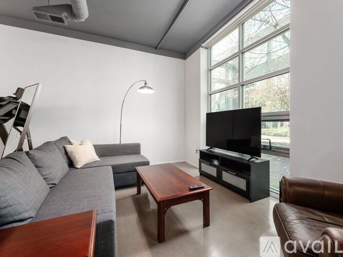 A living room with a grey couch, a wooden coffee table, and a television.
