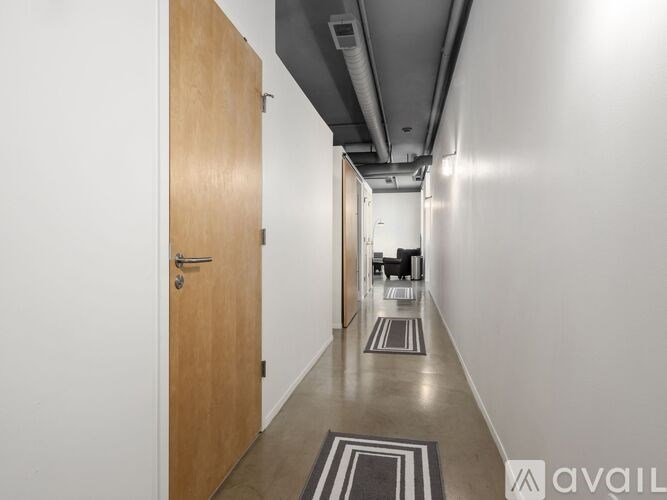 A long hallway with a door on the left and a carpeted floor.