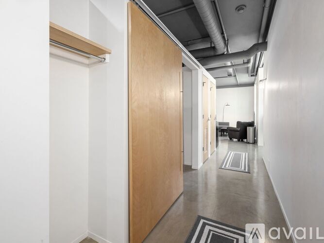 A hallway with a wooden door and a black and white rug on the floor.