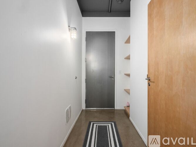 A hallway with a wooden door and a metal door on the other side.