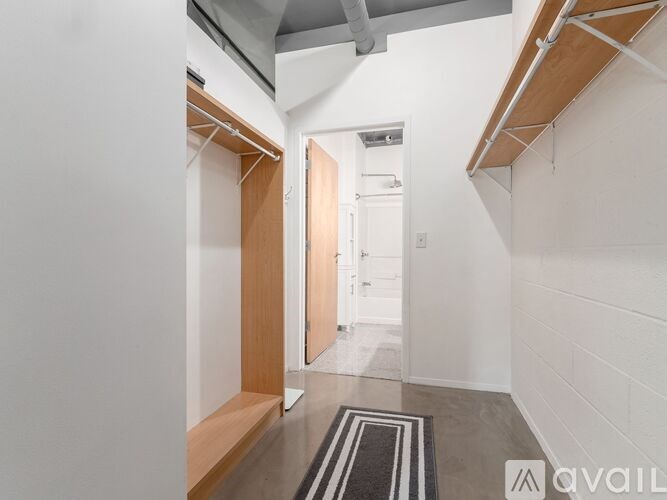 A hallway with a door at the end and a mat on the floor.