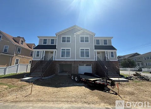 A house under construction with a trailer in front.