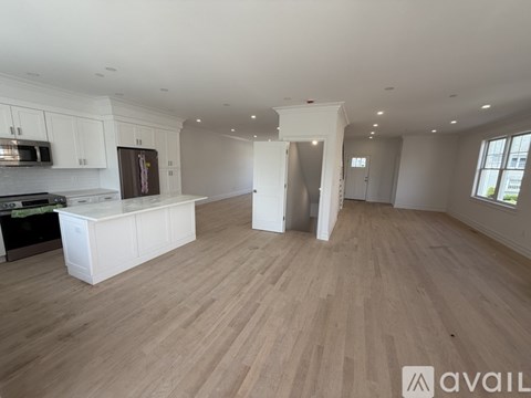 A spacious kitchen with white cabinets and a wooden floor.