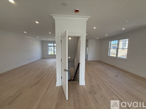 A room with wooden floors and a white door leading to another room.
