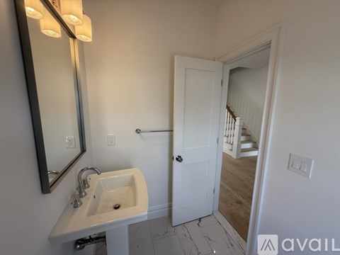 A bathroom with a sink, mirror, and a door leading to a hallway.