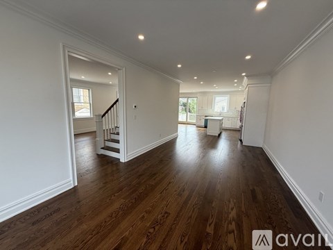 A spacious room with wooden flooring and white walls.