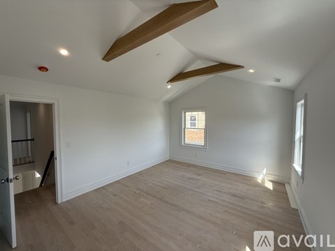 A spacious room with wooden floors and a window.