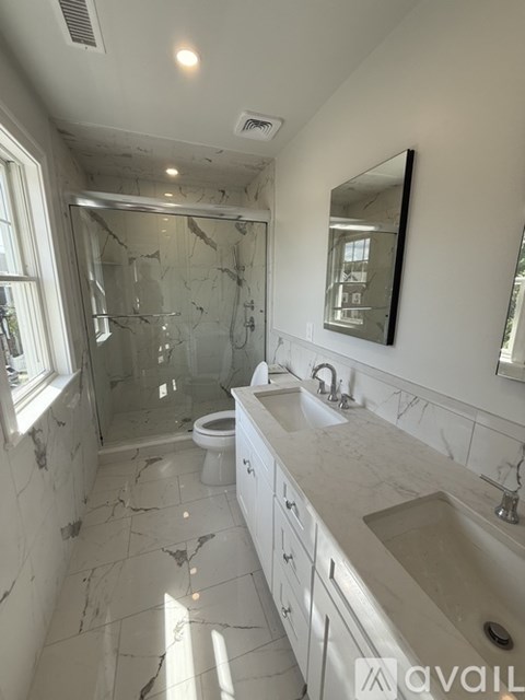 A bathroom with a marble floor and a large mirror.