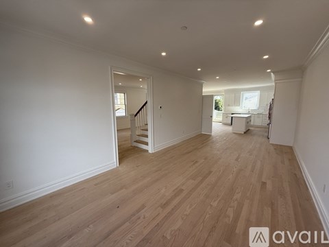 A spacious room with wooden flooring and white walls.