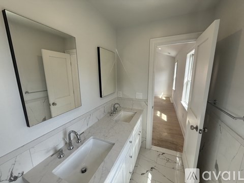 A bathroom with a marble countertop and two mirrors.