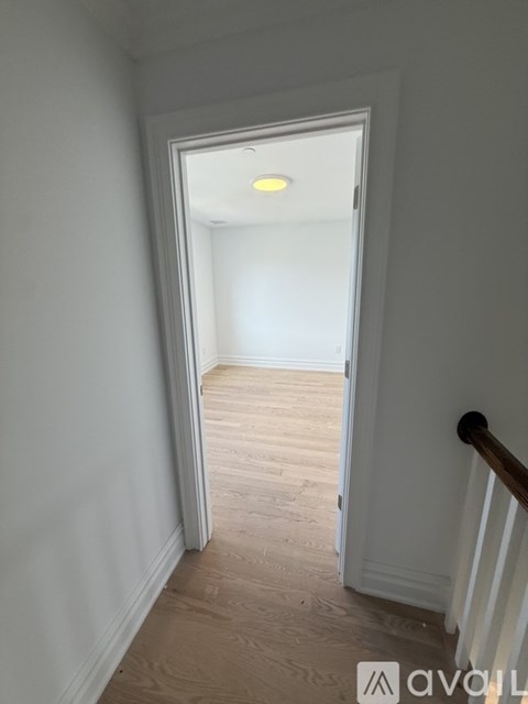 A hallway with a white door and wooden floor.