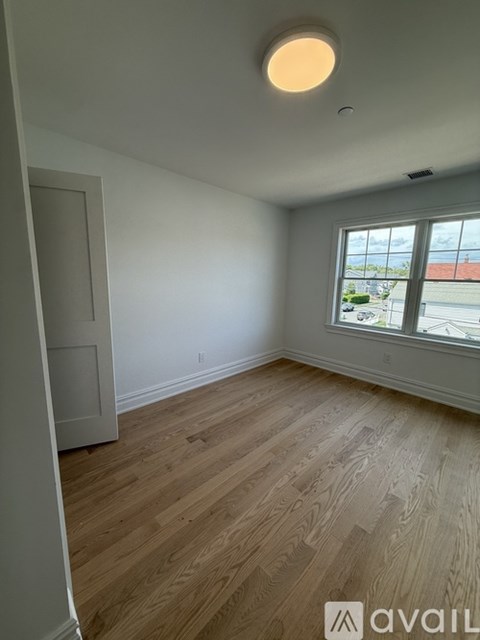 A room with wooden flooring and a window overlooking a street.