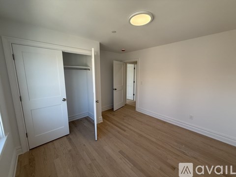 A room with a white door and a wooden floor.