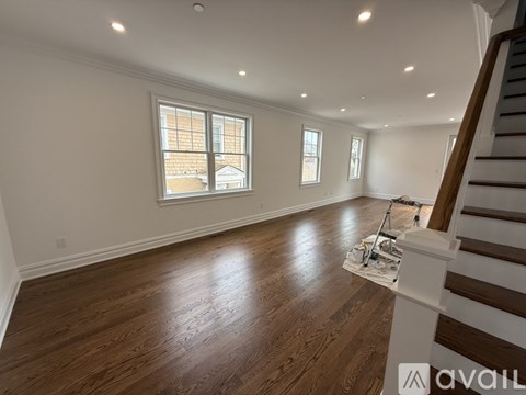 A room with wooden floors and a white door leading to another room.