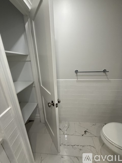 A white bathroom with a toilet and a towel bar.