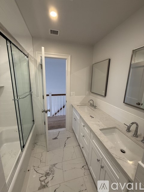 A bathroom with a marble counter top and a glass shower door.