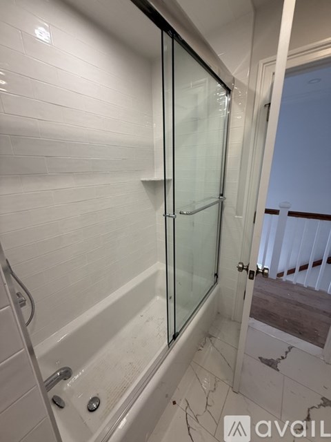 A bathroom with a glass shower door and a marble floor.