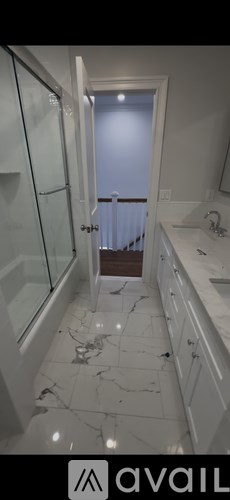 A room with wooden flooring and white walls, with a window on the left and a door on the right.