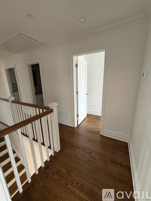 A wooden staircase with a white railing leads up to a bathroom.
