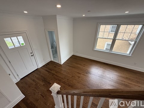 A room with wooden floors and a window with a view of a building.