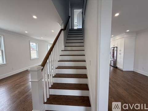 A staircase with wooden steps and white railings leads to a second floor.