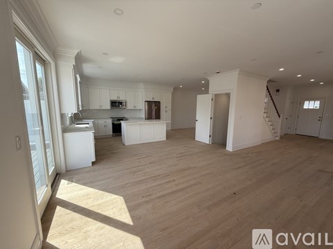 A spacious living room with wooden flooring and white walls.