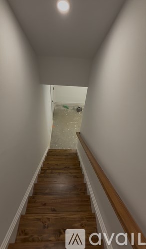 A hallway with wooden stairs leading to a greenish room.