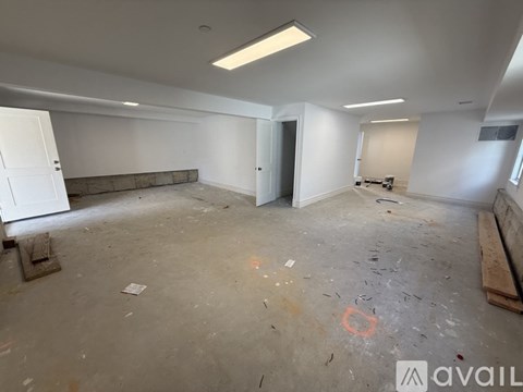 A large empty room with a concrete floor and white walls.