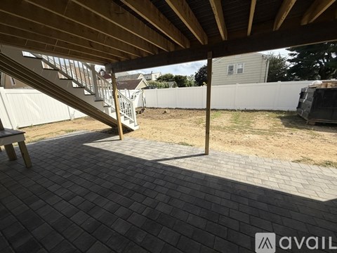 A patio with a wooden roof and brick flooring.