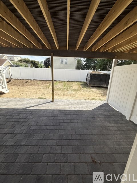 A backyard with a wooden roof and a brick patio.